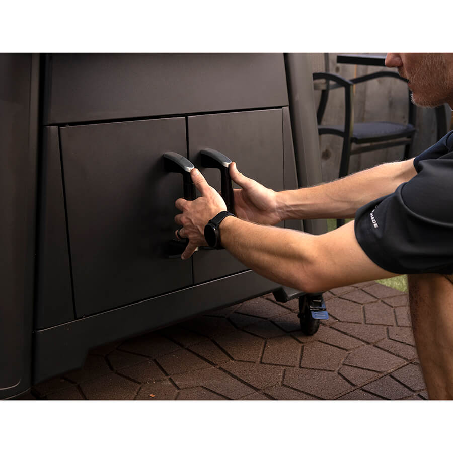 Pit Boss Competition Series Titan Wood Pellet Grill. Man crouching down to open up built-in grill storage cabinets