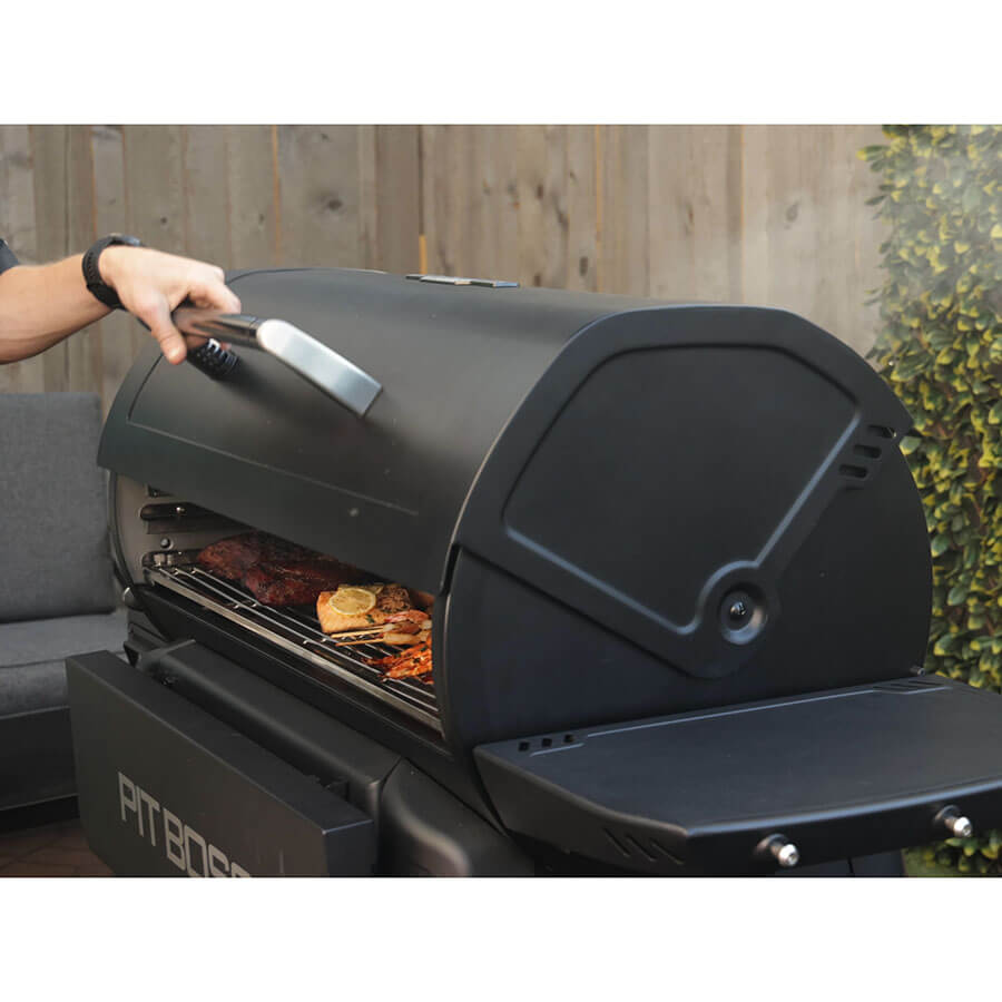 Pit Boss Competition Series Titan Wood Pellet Grill. Opening roll-top lid to reveal smoked and grilled food