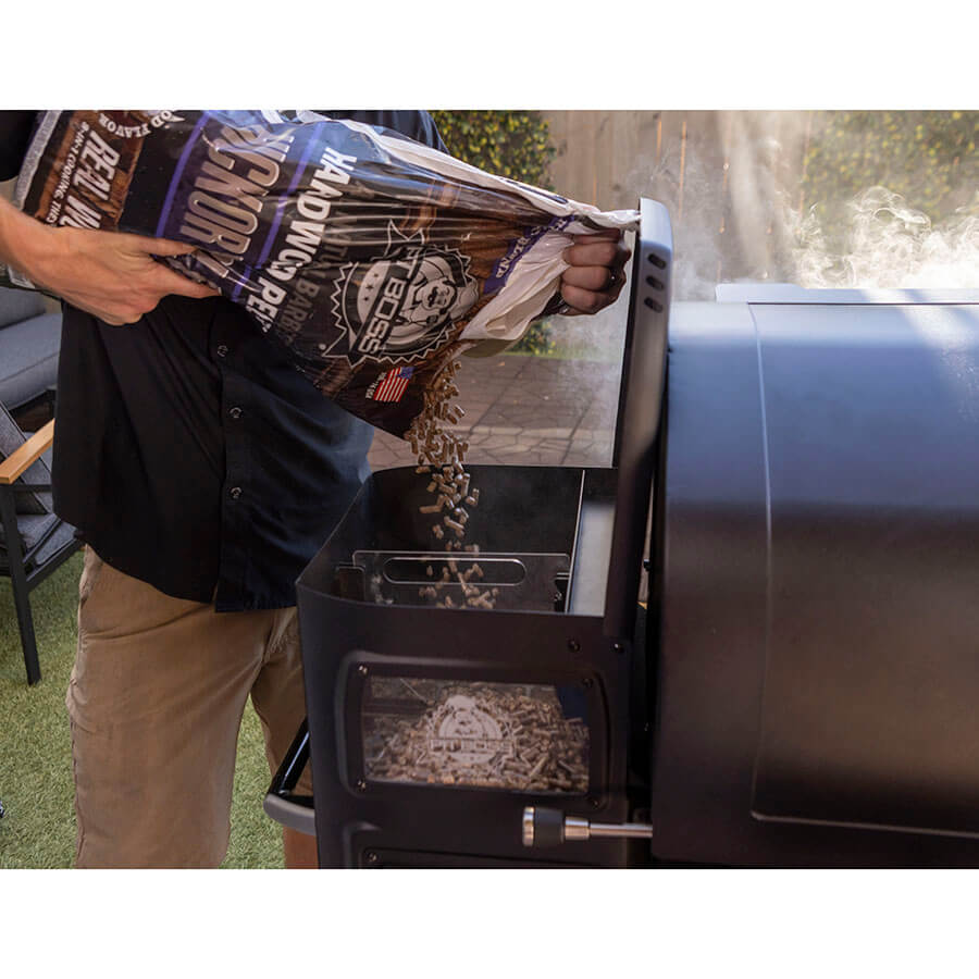 Pit Boss Competition Series Titan Wood Pellet Grill. Hickory Blend pellets being poured into wood pellet hopper with divider