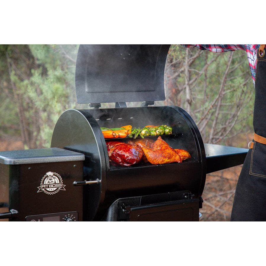 lifestyle photos of smoking grill with meats and veggies cooking inside