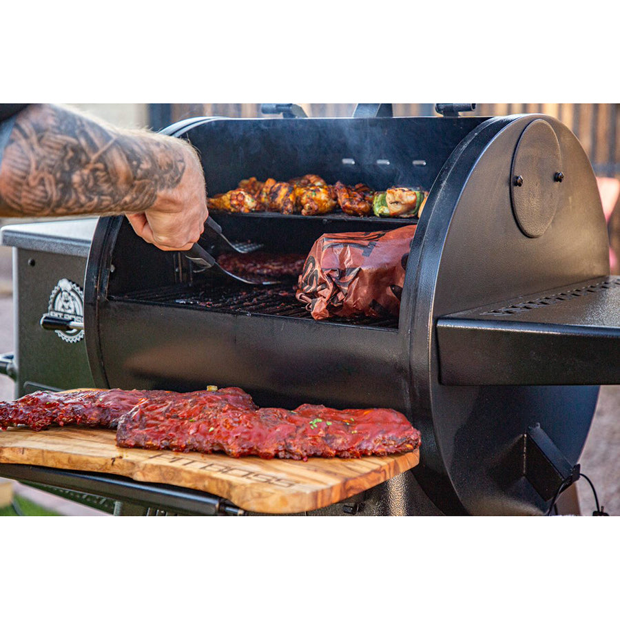 lifestyle image of food being taken out of grill and placed on wooden board on folding front shelf of grill