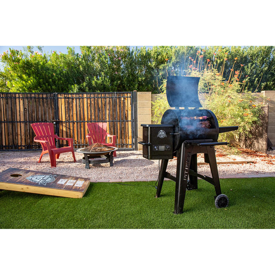 lifestyle image of grill in sunny backyard with smoke coming out of